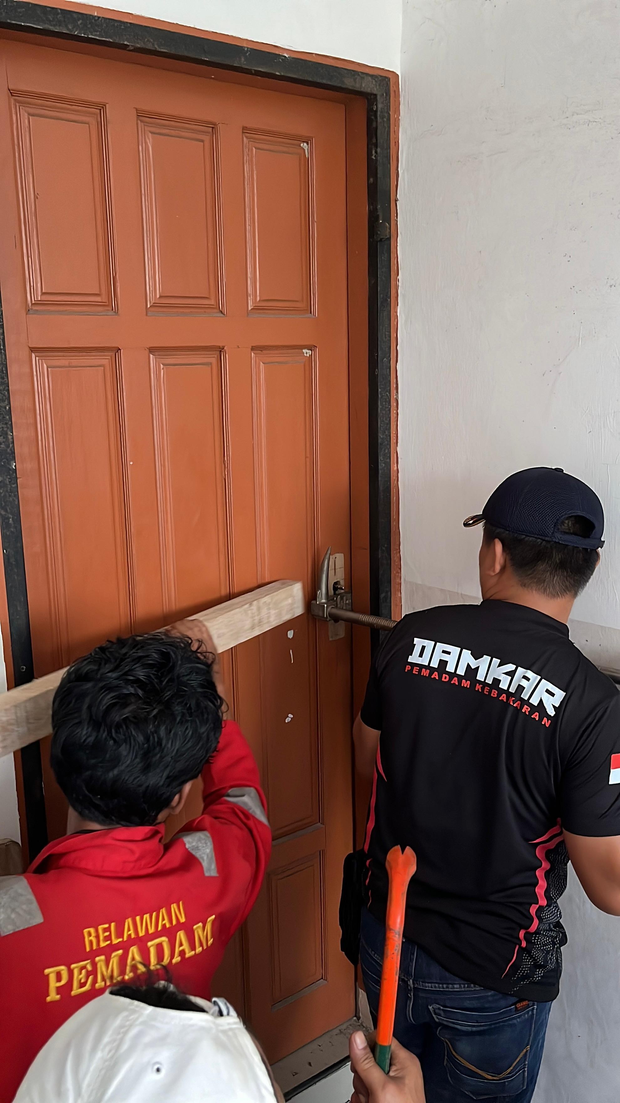 Personil Dinas Pemadam Kebakaran dan Penyelamatan berhasil membuka pintu rumah warga yang terkunci y