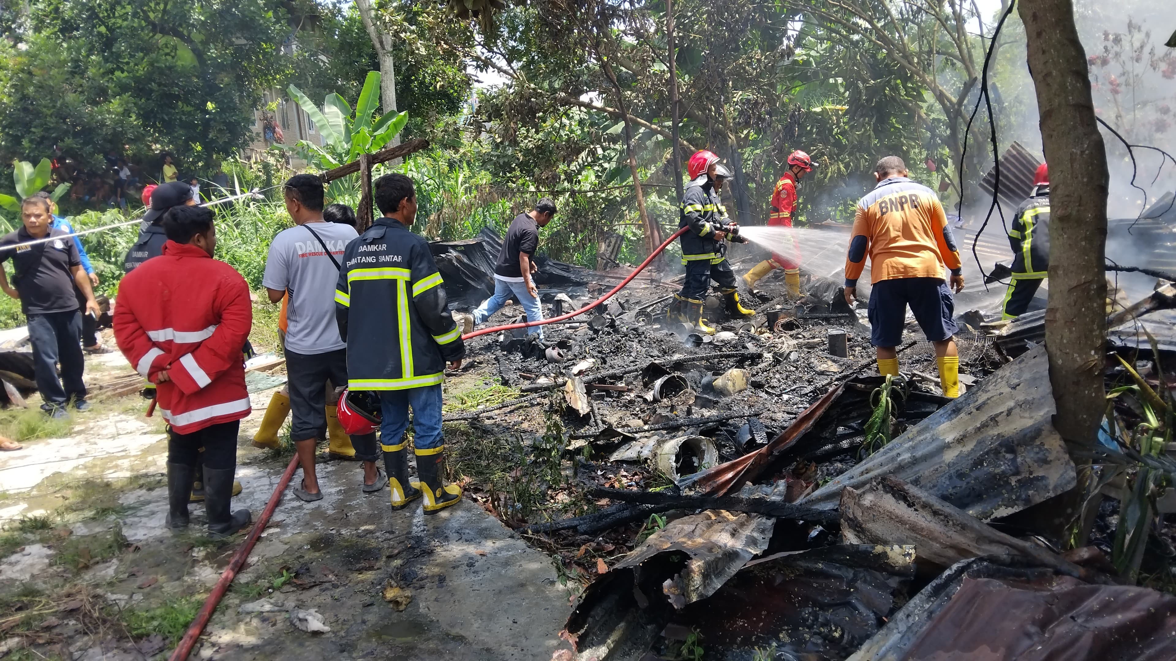 Personil Dinas Pemadam Kebakaran dan Penyelamatan melaksanakan pemadaman kebakaran rumah di Jl. Nag